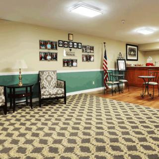 A cozy waiting room with patterned carpet, comfortable seating, and a reception area.