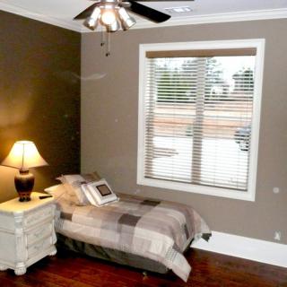 A cozy bedroom with a single bed, nightstand, and window.