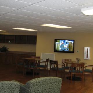 A cozy lounge with chairs, tables, and a wall-mounted television.