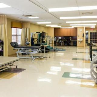 A spacious rehabilitation center equipped with various exercise machines and therapy tables.