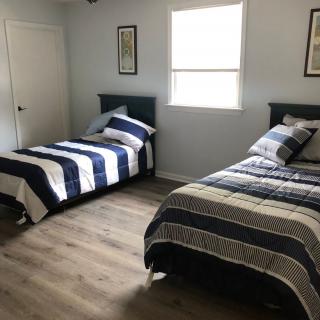 A minimalist bedroom featuring two twin beds with striped bedding and a wooden floor.