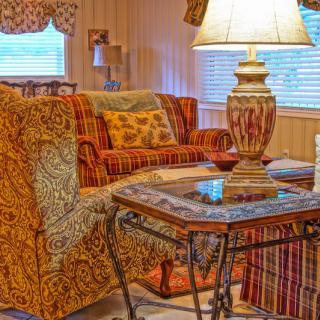 A cozy living room with patterned furniture, a decorative lamp, and a glass table.