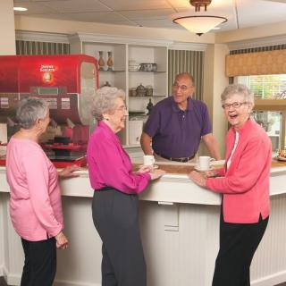 A group of seniors enjoying a conversation at a cafe counter.