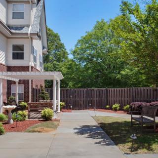 A well-maintained backyard with a pergola, patio, and outdoor seating surrounded by trees.