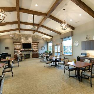 A welcoming community room featuring wooden beams, chandeliers, and ample seating.