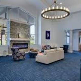 A modern lobby with a cozy seating area, featuring a chandelier and a fireplace.