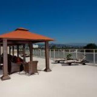 A sunny rooftop with a gazebo and outdoor furniture for relaxation.