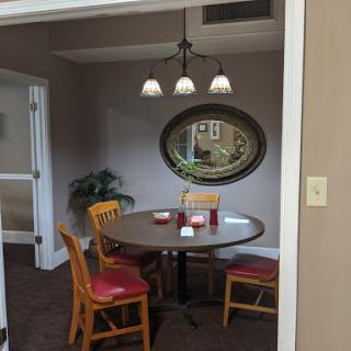 A cozy dining area featuring a round table, four chairs, pendant lighting, and a decorative mirror.
