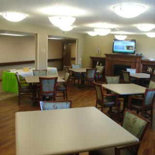 A spacious and well-lit common area featuring tables and chairs, suitable for dining or social gatherings.