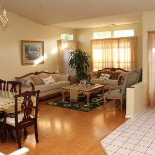 A cozy living room with an adjoining dining area, featuring classic furniture and warm lighting.