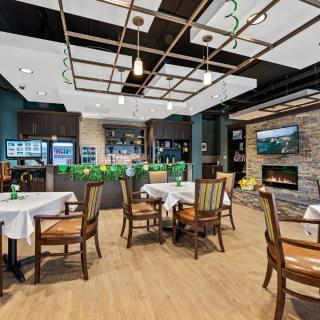 A modern restaurant interior with neatly arranged tables and chairs, featuring a cozy fireplace and a bar area.