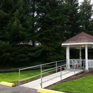 A charming gazebo with a ramp surrounded by lush greenery.