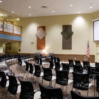 An empty conference room with a projector screen and rows of chairs arranged for a meeting.