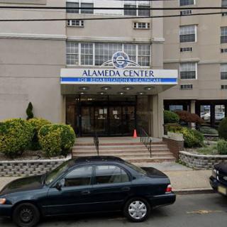 Entrance of a healthcare center with parked cars in an urban setting.