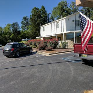 A view of a building with parked cars and an American flag waving in the foreground.