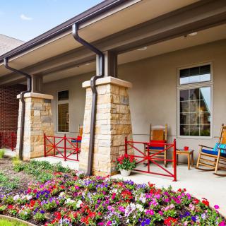 A welcoming porch with colorful flowers and rocking chairs.
