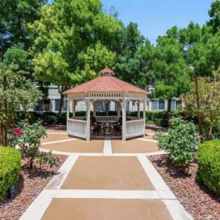 A charming gazebo in a beautifully landscaped garden with pathways and lush greenery.