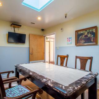 A meeting room with a large table, chairs, television, and a skylight.