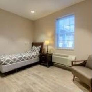 A minimalist bedroom with a single bed and a cozy chair.