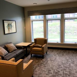 A cozy lounge area featuring comfortable seating and natural light streaming through large windows.