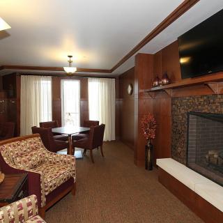 A cozy living room with a fireplace, comfortable seating, and a mounted television.
