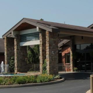 A building entrance with stone pillars and surrounding landscaping.