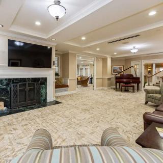 A luxurious living room with a fireplace, large television, and a piano.