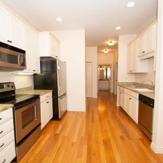 A modern kitchen with stainless steel appliances and wooden flooring.