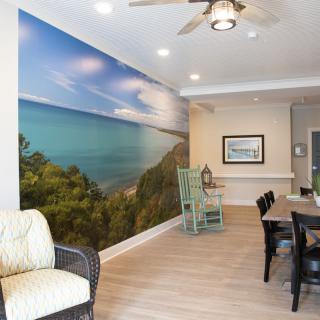 A modern living and dining space featuring a large coastal-themed wall mural.