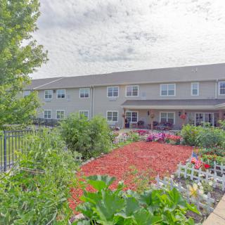 A well-maintained garden in front of a residential building with colorful flowers and greenery.