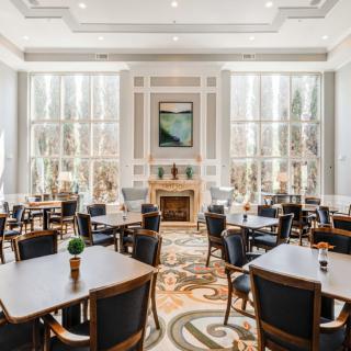 A spacious dining room with elegant decor, featuring large windows that allow natural light to fill the space.
