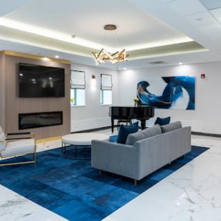 A modern living room featuring a blue-themed decor with stylish furniture and a grand piano.