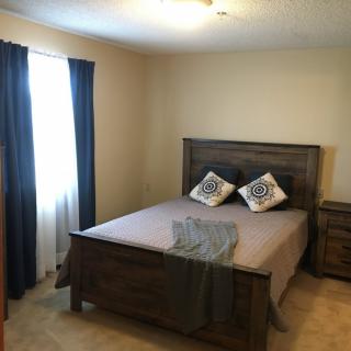 A cozy bedroom with a wooden bed frame, two decorative pillows, and dark blue curtains.