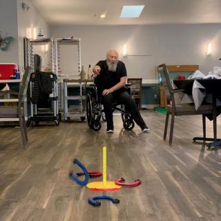 An elderly person in a wheelchair playing an indoor ring toss game.
