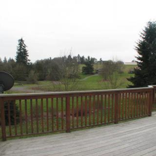 A wooden deck overlooking a lush green landscape with trees and a satellite dish in view.