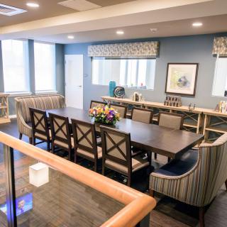 A well-lit, spacious dining or conference room featuring a long table with multiple chairs and decorative elements.