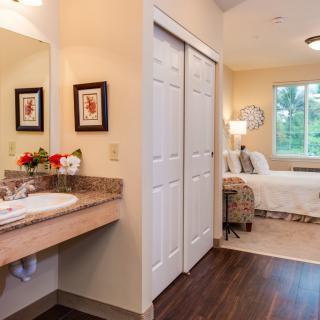 A cozy bedroom with an adjoining bathroom, featuring warm decor and ample natural light.