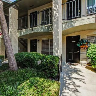 The exterior view of an apartment building with lush greenery and a private balcony.