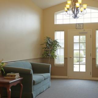 A cozy living room with a sofa, side table, and potted plant near the entrance door adorned by a chandelier.