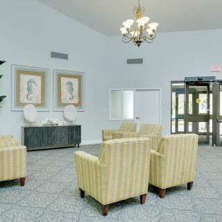 A well-lit lobby with striped chairs, a chandelier, and decorative artwork on the walls.
