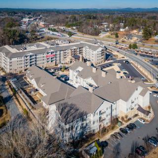 Aerial view of a residential community with buildings, roads, and parking lots surrounded by trees.