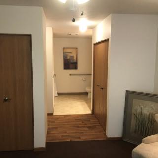 A cozy hallway featuring wooden doors and wall art under warm lighting.