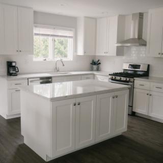 A modern kitchen with white cabinets, a central island, and stainless steel appliances.