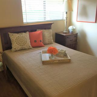A neatly arranged bedroom with decorative pillows and a tray on the bed.