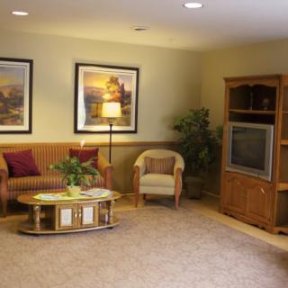A cozy living room with a sofa, armchair, and television.