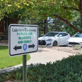 A parking sign indicating designated spaces for residents and family in a residential area, with cars parked nearby and greenery surrounding the scene.