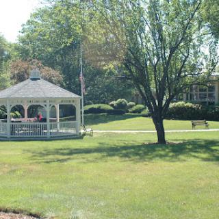 A peaceful park scene featuring a gazebo surrounded by lush greenery.