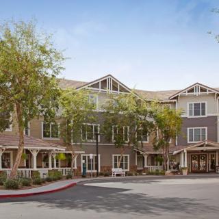 A charming residential building surrounded by trees on a sunny day.