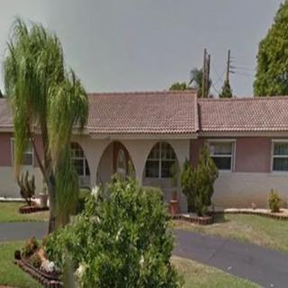 A suburban house with a well-maintained front yard and palm trees.