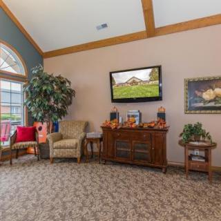 A cozy living room with a TV, armchairs, and decorative elements.